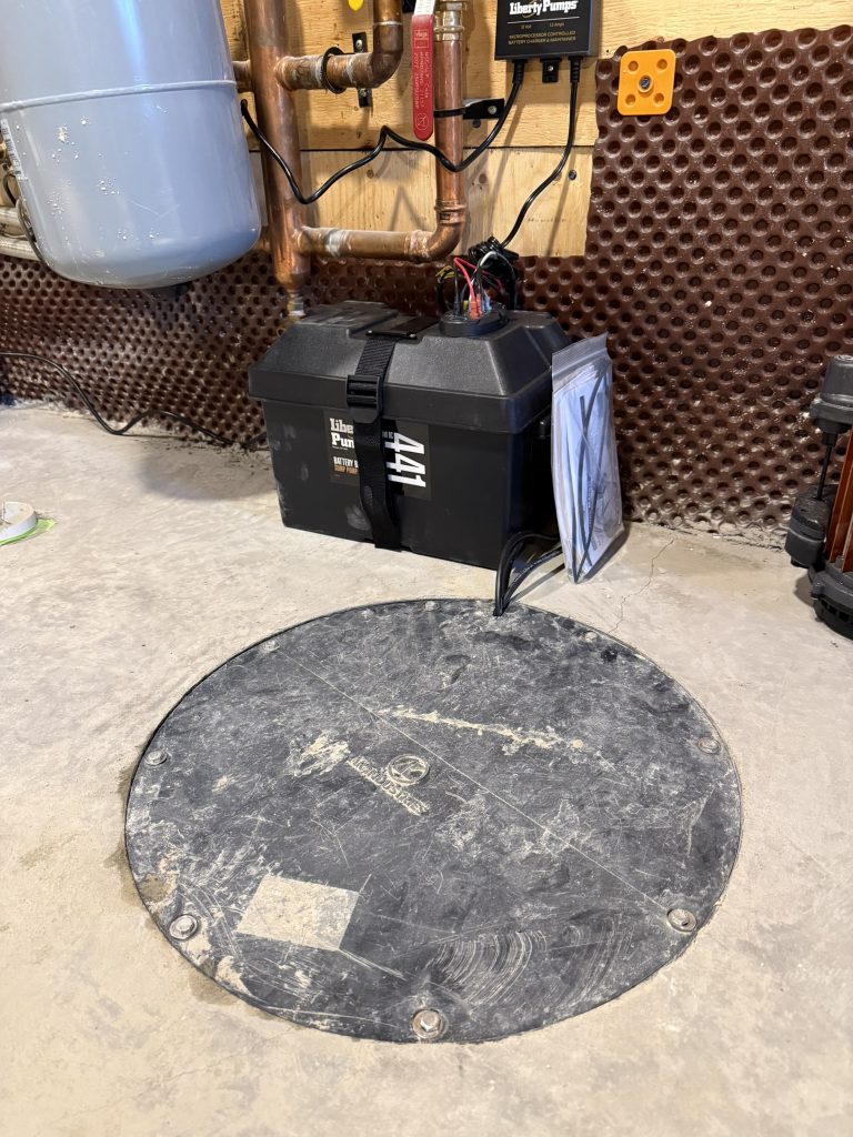 Round access cover on concrete floor for a battery backup sump pump