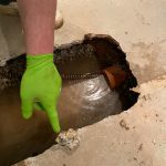 Hand pointing at water-filled drain hole
