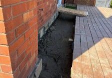 Excavated area beside wooden deck.