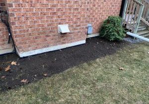Dirt area beside brick wall after waterproofing completed