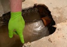Hand pointing at water-filled drain hole
