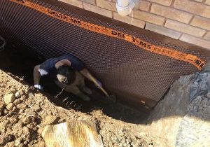 Person digging near foundation wall