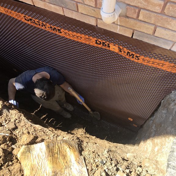 Person digging near foundation wall