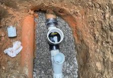 Excavated area with plumbing installation visible.