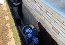 Workers applying waterproofing in trench